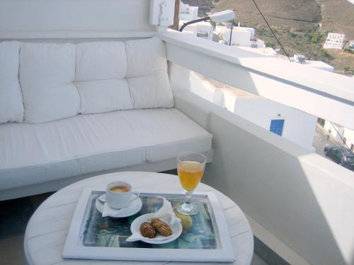 a tray of food and a drink on a table on a balcony at Studios Anemomilos in Astypalaia Town