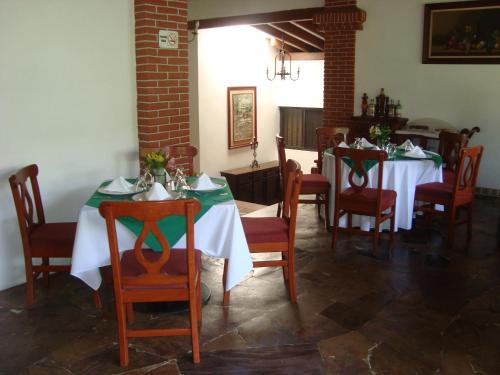 a dining room with two tables with green and white tablecloths at Hotel Vista Hermosa in Cuernavaca