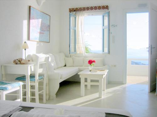 a white living room with a white couch and tables at Studios Anemomilos in Astypalaia Town