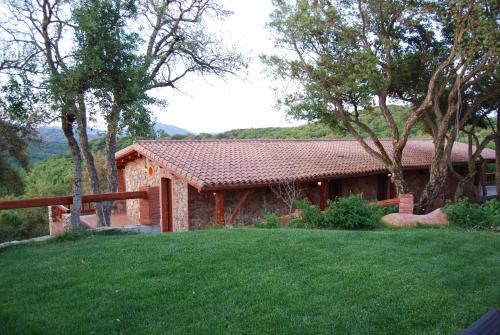 a house with a green lawn in front of it at La Quercia in Arbus