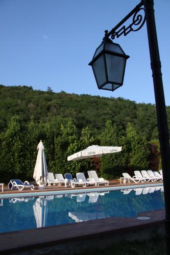 a group of chairs and an umbrella and a pool at Villa Felcaro - Relais, Lodge & Restaurant in Cormòns