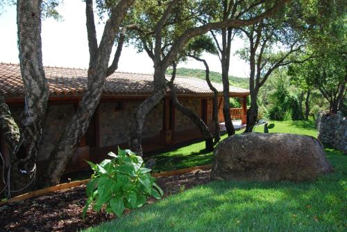 a house with a yard with a rock and trees at La Quercia in Arbus