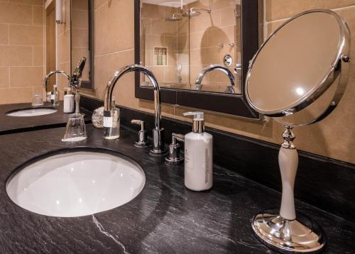 a bathroom with a sink with a mirror and a soap dispenser at Glencoe House in Glencoe