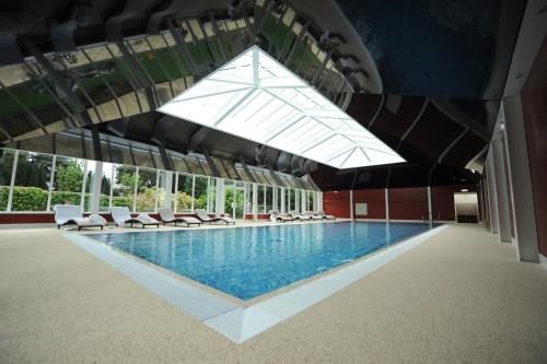 a large swimming pool with white chairs and windows at The Parsonage Hotel & Spa in York