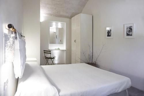 a white bedroom with a white bed and a chair at Masseria Capece in Cisternino