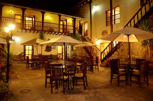un restaurante con mesas y sillas y sombrillas por la noche en Unaytambo Boutique Hotel Cusco, en Cusco