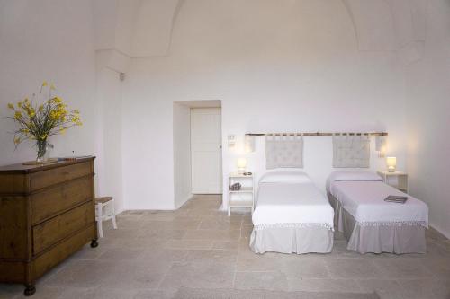 a white bedroom with two beds and a dresser at Masseria Capece in Cisternino
