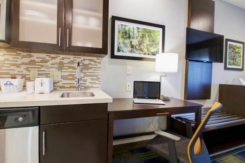 a kitchen with a sink and a laptop on a desk at Days Inn & Suites by Wyndham Port Arthur in Port Arthur