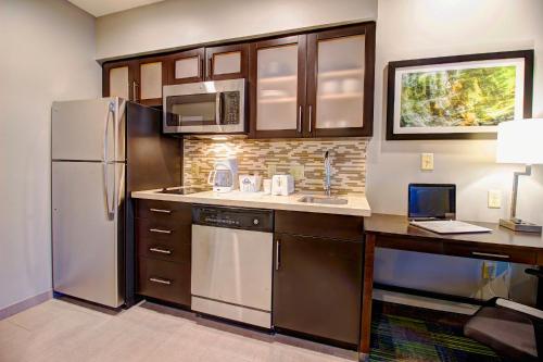 a kitchen with a refrigerator and a laptop on a counter at Days Inn & Suites by Wyndham Port Arthur in Port Arthur