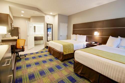 a hotel room with two beds and a desk at Days Inn & Suites by Wyndham Port Arthur in Port Arthur