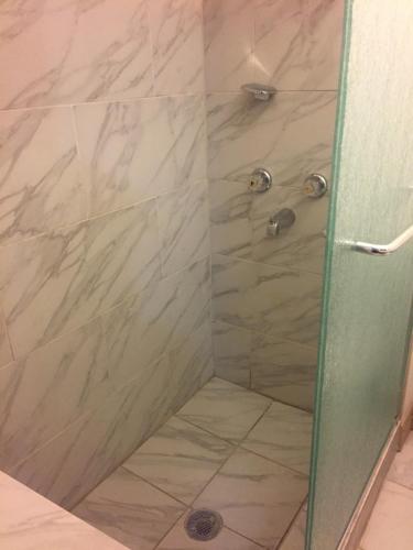 y baño con ducha y puerta de cristal. en Surf Motel and Apartments en Galveston