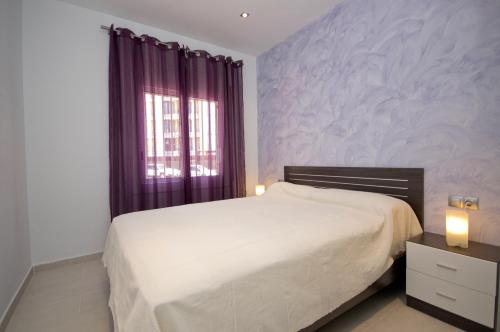 1 dormitorio con cama blanca y ventana en InmoSantos Oasis E3, en Roses
