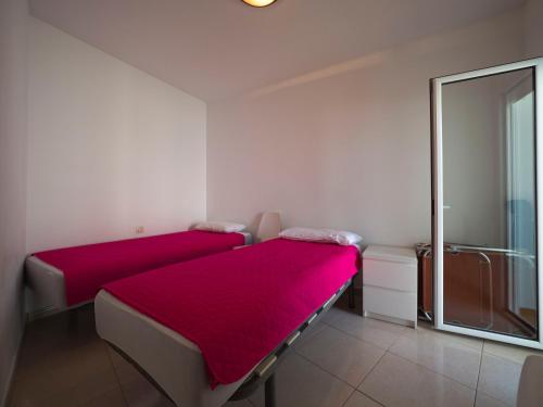 1 dormitorio con 2 camas con sábanas rojas y ventana en InmoSantos Oasis D4, en Roses