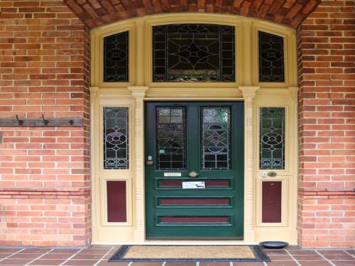 a green door and windows on a brick building at Penghana Bed and Breakfast in Queenstown