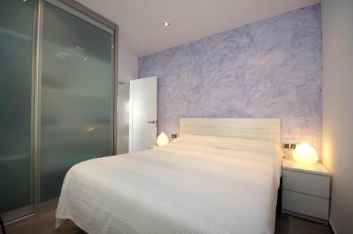 ロザスにあるInmoSantos Oasis B7の紫の壁のベッドルーム1室(白いベッド1台付)
