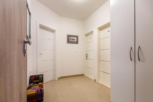 a hallway with white closet doors and a colorful chair at Rooms Split in Split