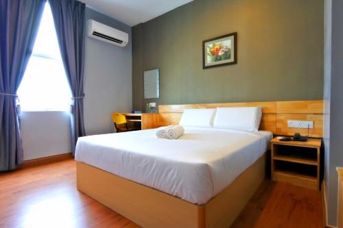 a bedroom with a large white bed and a window at Hotel Dutaria in Ipoh