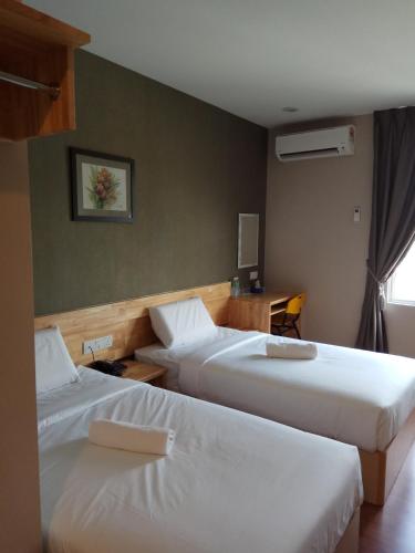 a hotel room with two beds and a desk at Hotel Dutaria in Ipoh