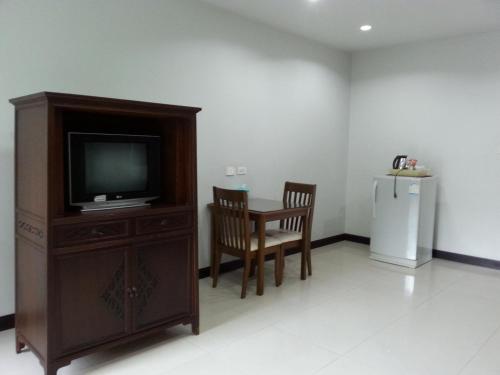 a living room with a tv and a table and a refrigerator at C.A.P Mansion in Phuket Town