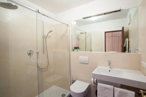 uma casa de banho com um chuveiro, um lavatório e um WC. em Hotel Weingarten em Naturno