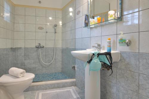 een badkamer met een douche, een wastafel en een toilet bij Rolandos Apartments in Agios Gordios
