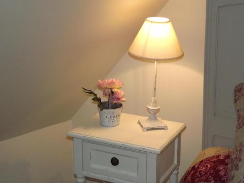 a table with a lamp and a vase of flowers on it at Le Compostelle de Conques in Conques-en-Rouergue