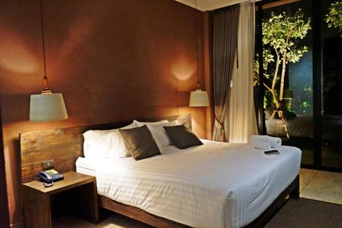 a bedroom with a large white bed and a table at The Glory River Kwai Hotel in Kanchanaburi