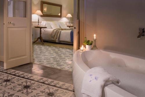 a bathroom with a tub and a bedroom with a bed at Jardí de Ses Bruixes Boutique Hotel in Mahón