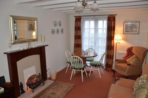 salon z kominkiem, stołem i krzesłami w obiekcie The Little Elbow Room w mieście Totnes