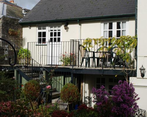 a white house with a balcony with flowers at The Little Elbow Room in Totnes