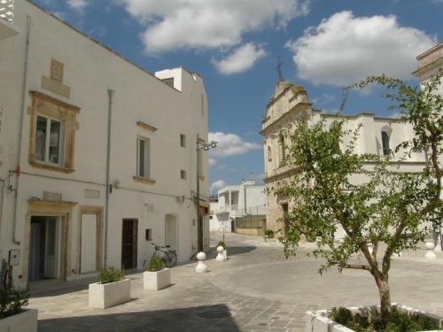 una plaza de la ciudad con edificios blancos y un árbol en Dimore Santagaeta, en Racale
