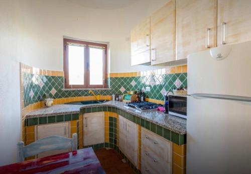 ポルト・サン・パーオロにあるLe Case del Mareの緑と黄色のタイルを用いたキッチン(白い冷蔵庫付)