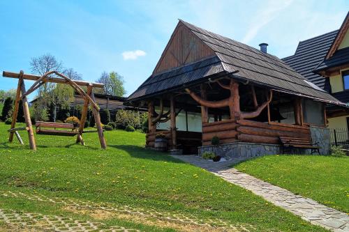 a log cabin with a swing and a playground at Pokoje u Borzana in Biały Dunajec