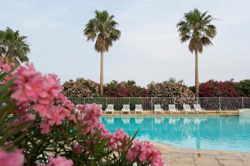 una piscina con palmeras y flores rosas en Residence Cap Hermes - maeva Home, en Fréjus