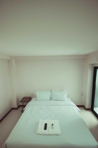 a large white bed with a book on it at Don Muang Hotel in Bangkok