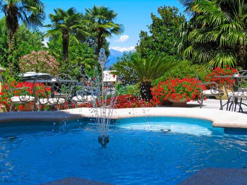 a fountain in a pool in a garden with flowers at Hotel Villa Delle Palme in Cannobio