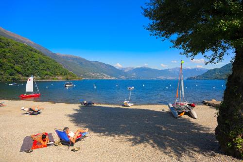 a group of people laying in chairs on a beach at Hotel Villa Delle Palme in Cannobio