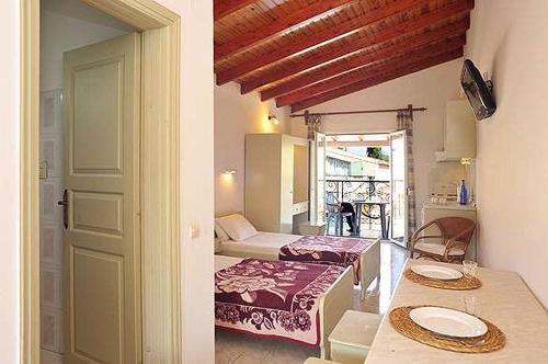 Philippos Kassiopi Apartments في كاسيوبي: غرفة مع طاولة وسرير