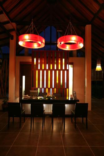 a dining room with a table and chairs under lights at Ayara Villas - SHA Extra Plus in Khao Lak