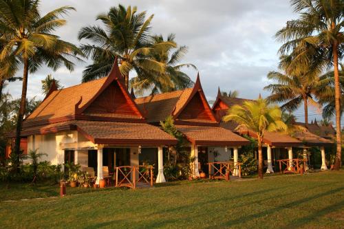 a house with palm trees in front of it at Ayara Villas - SHA Extra Plus in Khao Lak
