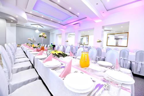 un largo salón de banquetes con mesas blancas y sillas blancas en Malibu Kalisz, en Kościelna Wieś