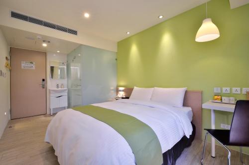 a bedroom with a large bed with a green wall at Green Hotel - Fengjia in Taichung