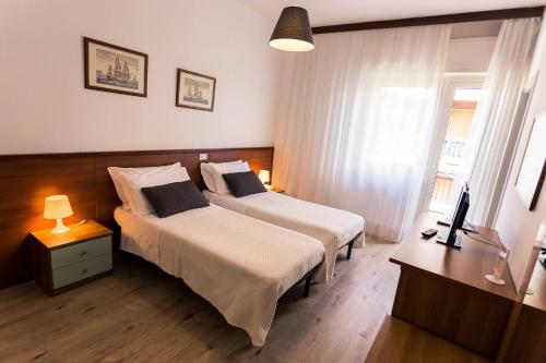 モンテジルヴァーノにあるHotel Antagosのベッド2台と窓が備わるホテルルームです。