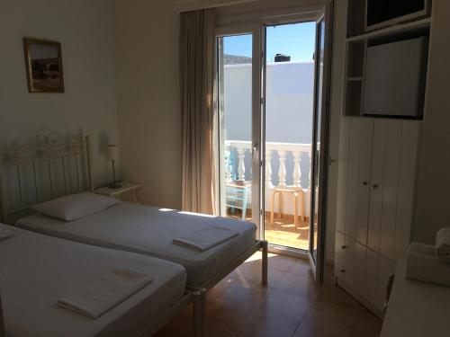 a bedroom with two beds and a sliding glass door at Nikoleta Rooms in Tinos Town