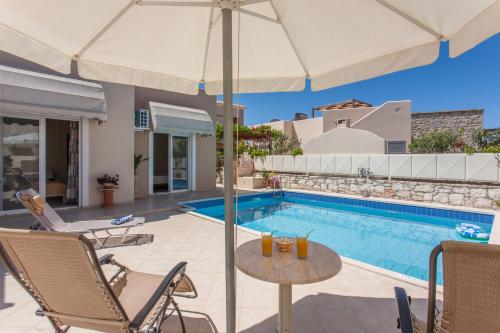 einen Pool mit einem Tisch, Stühlen und einem Sonnenschirm in der Unterkunft Villa Nopigia Somina in Kissamos