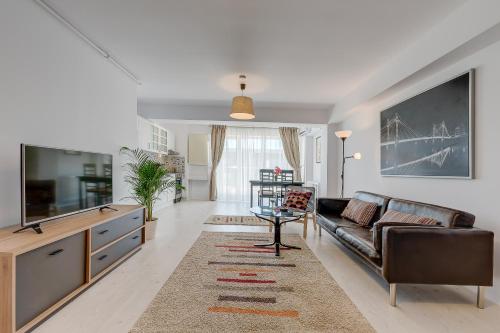 a living room with a couch and a tv at Bucharest Airport Suites & Villas in Otopeni