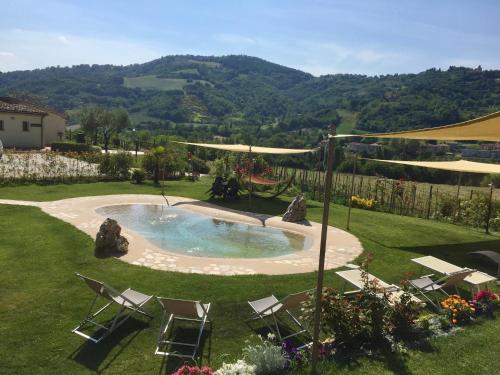 a pool in a yard with chairs and a fence at Locanda Montelippo in Colbordolo