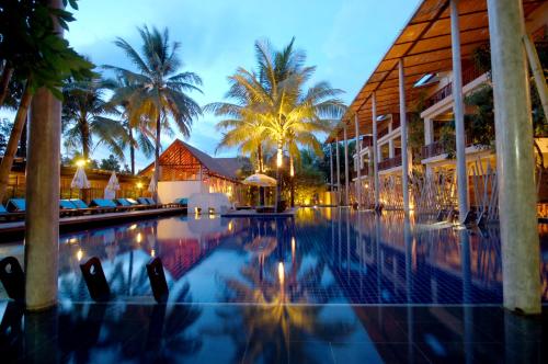 a resort swimming pool with palm trees in the background at Ayara Villas - SHA Extra Plus in Khao Lak