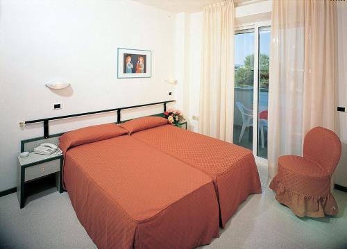 a bedroom with a bed and a chair and a balcony at Residence Hotel Club House in Cattolica