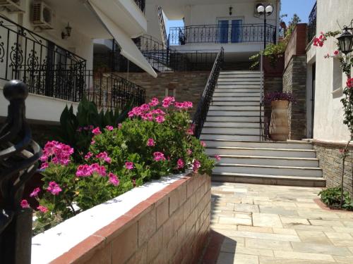a retaining wall with flowers in front of a house at Lazaridis Luxury Studios & Apartments in Nea Roda